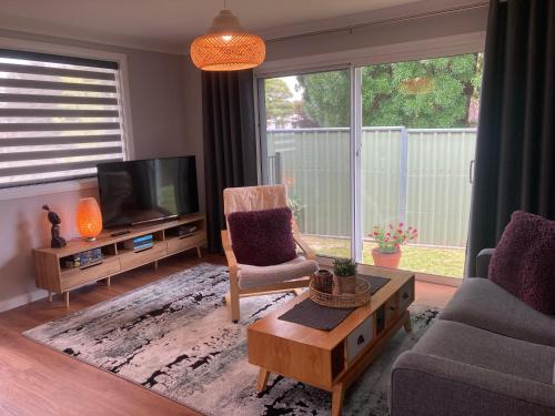 a living room with a tv and a chair and a table at Oleander Cottage in Orange
