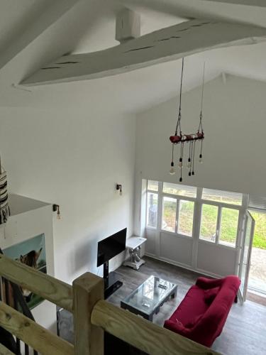 a living room with a red couch and a table at Equizen33 maison zen et ressourçante in Saint-Mariens