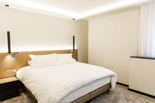 a bedroom with a bed with white sheets and a window at Suite Montrachet 4 personnes vue cathédrale 1 Place de parking in Dijon