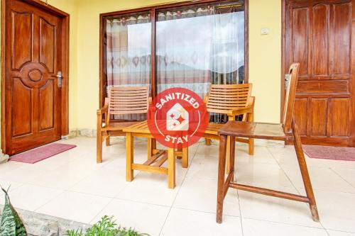 a sign on a table and chairs in a room at Hotel O Ujung Samalas HomestayNearLapangan Sembalun Bumbung in Labuan Lombok