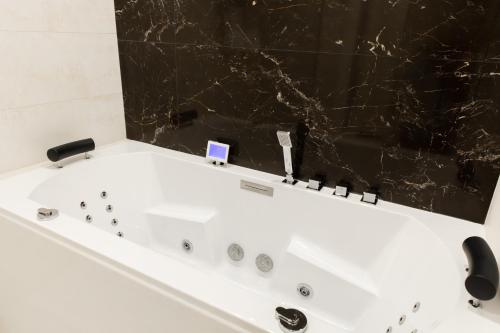 a white bath tub with a black marble wall at Suite Montrachet 4 personnes vue cathédrale 1 Place de parking in Dijon