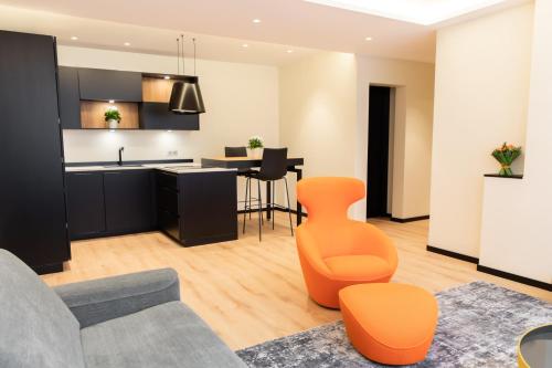 Il comprend une cuisine ouverte et un salon avec une chaise orange. dans l'établissement Suite Montrachet 4 personnes vue cathédrale 1 Place de parking, à Dijon