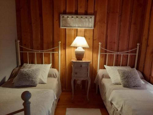 ein Schlafzimmer mit 2 Betten und einer Lampe auf einem Nachttisch in der Unterkunft Gîte Saint-Régis-du-Coin, 3 pièces, 4 personnes - FR-1-496-268 in Saint-Régis-du-Coin