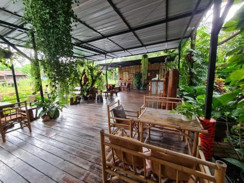 un patio con mesas de madera, sillas y plantas en Baan Canalee (บ้านคานาลี), en Phra Nakhon Si Ayutthaya