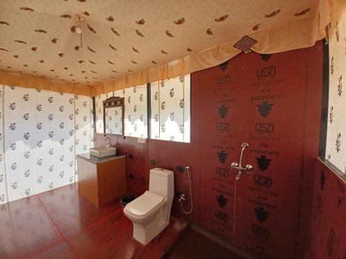 a bathroom with a toilet and red walls at Hotel Green Haveli - A Heritage and Hill View Hotel , Pushkar in Pushkar