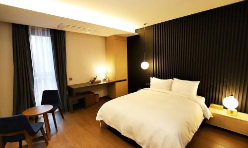 a bedroom with a large white bed and a desk at Gangneung Grey Hotel in Gangneung