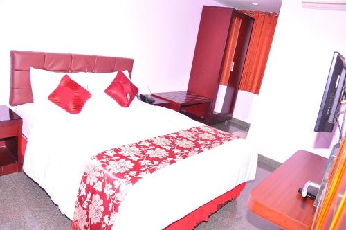 a bedroom with a white bed with red pillows at RATNA FOREVER NITTE in Kārkāl