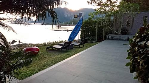 a patio with chairs and an umbrella next to the water at Blue Orchid Beach Krabi - SHA Certified in Ao Nam Mao