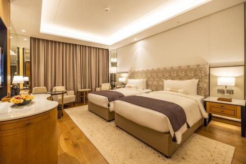 a hotel room with two beds and a desk at The Leela Bhartiya City Bengaluru in Bengaluru