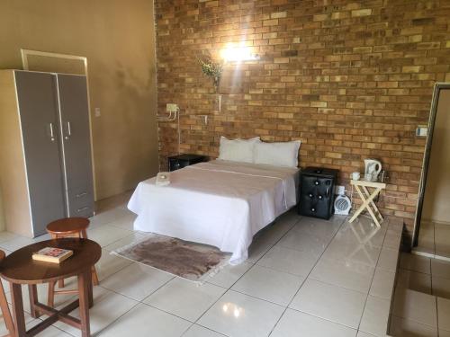 a bedroom with a bed and a brick wall at ALBATROSSWAYS LODGE in Sandton