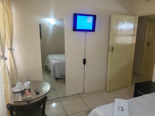 een kamer met een televisie aan de muur met een spiegel bij ALBATROSSWAYS LODGE in Sandton