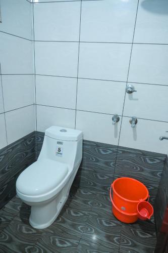 a bathroom with a toilet and an orange bucket at Janoos Homestay in Kumarakom