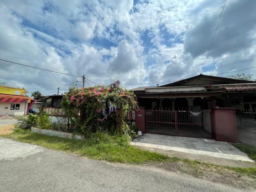 a house with a gate and a bush with flowers at MIA FAMILIA HOMESTAY in Cukai