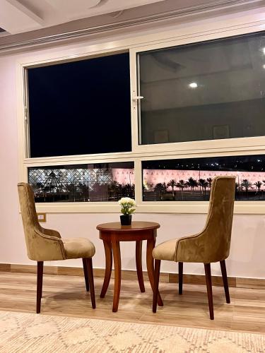 two chairs and a table in front of a large window at New Museum Guest House, Pyramids View in Cairo