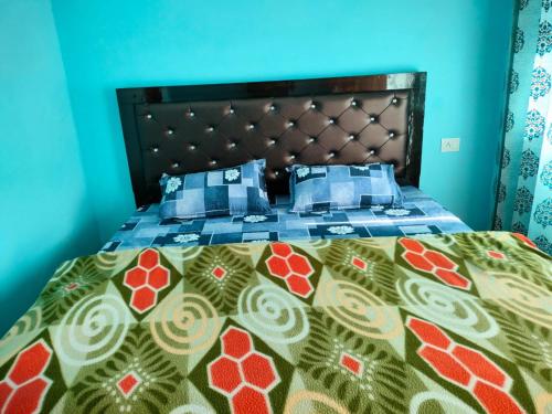 a bedroom with a bed with a blue wall at Pandava's Cafe & Stay in Chopta