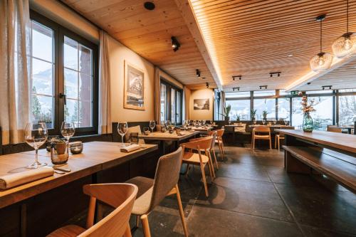 a restaurant with wooden tables and chairs and windows at Hotel Fiescherblick in Grindelwald