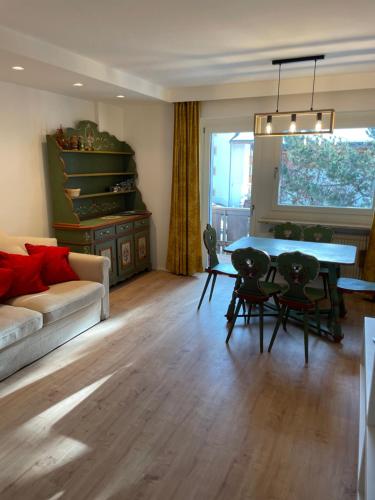 ein Wohnzimmer mit einem Tisch, Stühlen und einem Sofa in der Unterkunft Appartamento a Dobbiaco nel cuore delle Dolomiti in Toblach