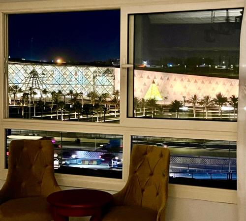 a window with two chairs and a view of a city at New Museum Guest House, Pyramids View in Cairo