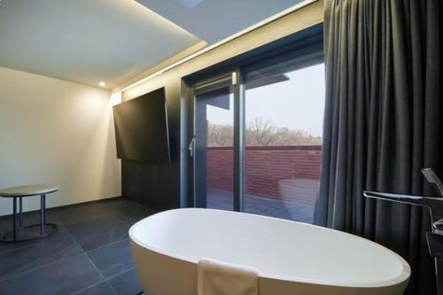 a bathroom with a white tub and a large window at Hotel TARA in Seoul