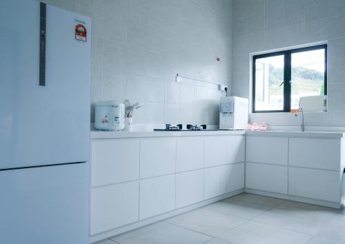 a white kitchen with white cabinets and a window at Comfy Sofy 23- Balcony Garden (Night market) in Tanah Rata
