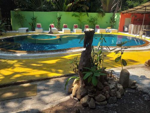 a swimming pool with a palm tree next to at Kamrai Homestay in Ko Chang