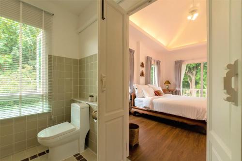 Phi Private Villa: Luxury Thai with Riverview في شيانغ ماي: غرفة نوم بسرير ومرحاض ونافذة