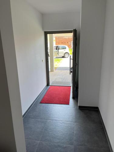 a hallway with a red rug and a door with a red carpet at Ferienhof Elbaue in Schönebeck