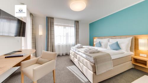 a hotel room with a large bed and a desk at R&R Residenzen Aparthotel in Mitterbach