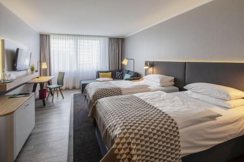 ノイスにあるHoliday Inn Düsseldorf-Neuss, an IHG Hotelのベッド2台とテレビが備わるホテルルームです。
