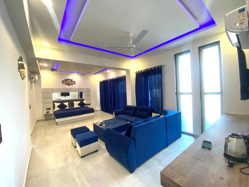 uma sala de estar com um sofá azul e um quarto com janelas em The Metro Stay By F9 Hotels-Near Sector 18 Metro Station Noida em Noida