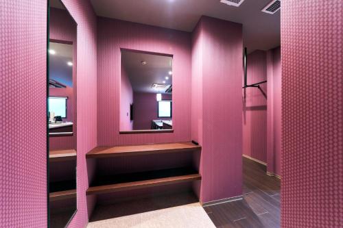 Baño de color rosa con espejo y paredes rosas en Rakuten STAY Kokura Station Family Room en Kitakyushu