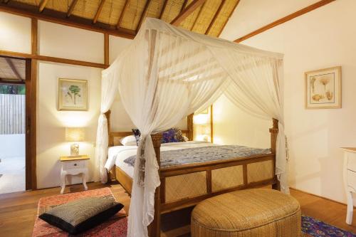 a bedroom with a canopy bed and a chair at Villa Terra in Gili Trawangan