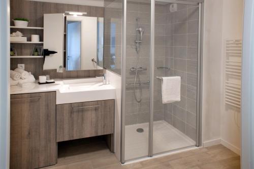 uma casa de banho com um chuveiro, um lavatório e um espelho. em Domitys l'Amarante em Cahors
