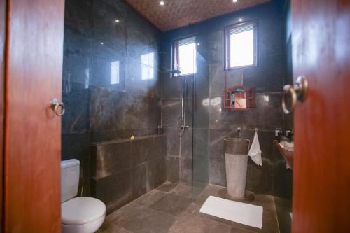 a bathroom with a shower with a toilet and a glass door at Gayatri in Ubud