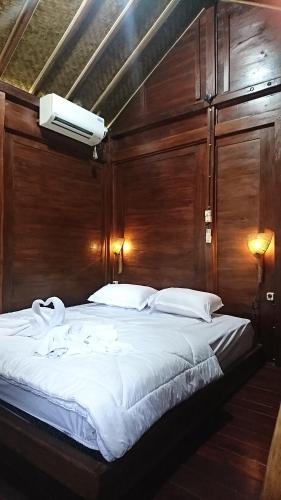 una camera con un grande letto e una parete in legno di Wisma Andany a Jepara