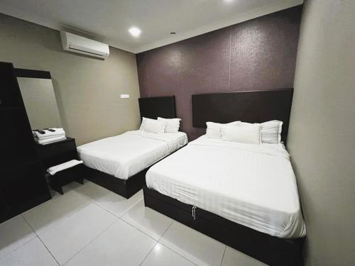 a hotel room with two beds with white sheets at Hotel Sagittario in Ipoh