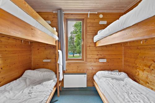 two bunk beds in a wooden cabin with a window at First Camp Nydala-Umeå in Umeå