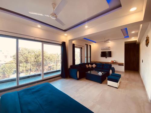 a living room with a blue couch and a large window at The Metro Stay By F9 Hotels-Near Sector 18 Metro Station Noida in Noida
