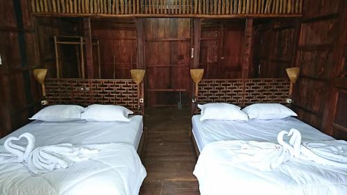 two beds in a room with wooden walls at Wisma Andany in Jepara