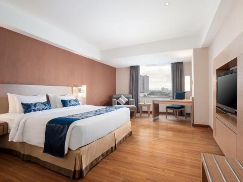 a hotel room with a bed and a flat screen tv at Grand City Hall Hotel & Serviced Residences in Medan