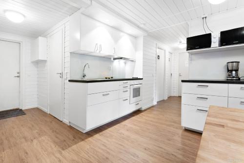 a white kitchen with white cabinets and a wooden floor at First Camp Nydala-Umeå in Umeå