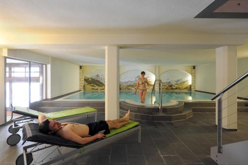 mężczyzna leżący na tratwie w basenie w obiekcie Hotel Krone Lenk w mieście Lenk