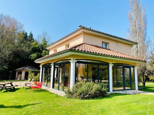 a house with a conservatory with a table and chairs at Domaine de Suzel in Vignieu