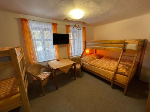 a bedroom with bunk beds and a table and a chair at Penzion Pohádka in Železná Ruda