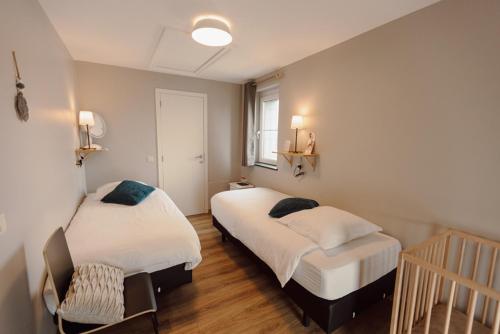Un dormitorio con 2 camas y una silla. en Le Relais De La Motte, en Soignies