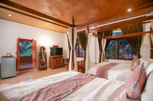 a bedroom with two beds and a flat screen tv at Gayatri in Ubud