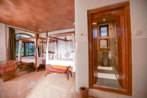 a room with a bedroom with a bed and a mirror at Gayatri in Ubud
