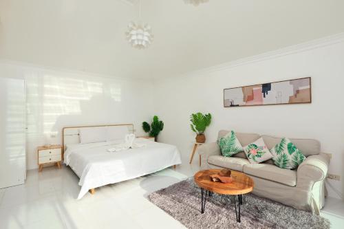 Daydream villa resort في شاطيء باتونغ: غرفة معيشة بيضاء مع سرير وأريكة
