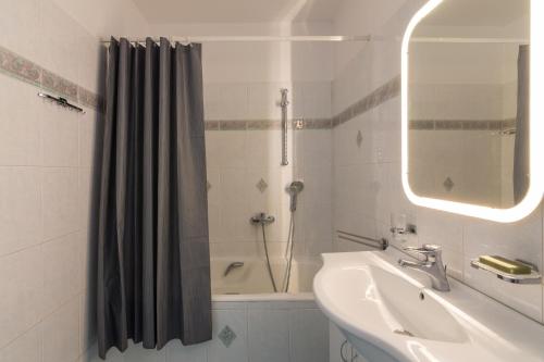 een badkamer met een wastafel en een douche met een douchegordijn bij Elegant Apartment With Acropolis View in Athene