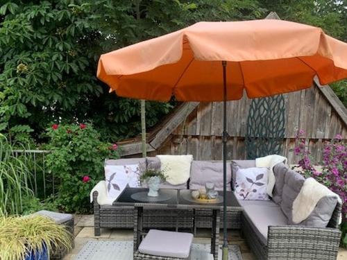 - un parasol orange sur une terrasse avec un canapé et une table dans l'établissement Ferienwohnungen Lemma, à Möhnesee